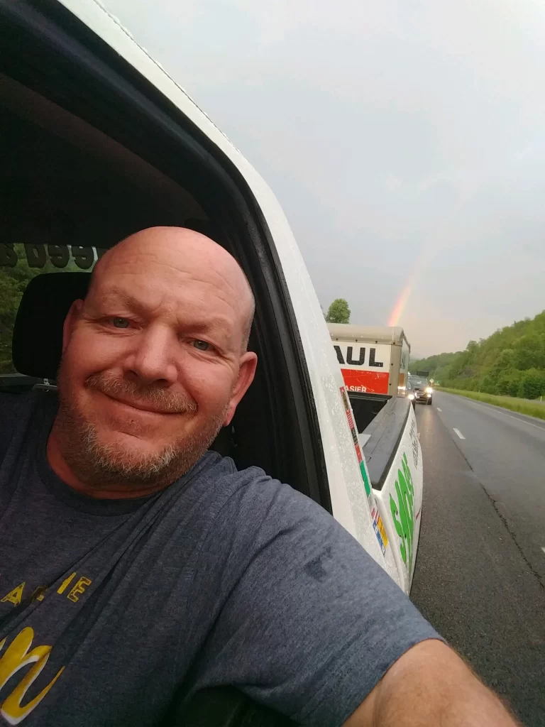 Zak with a U-Haul trailer and a rainbow in the background